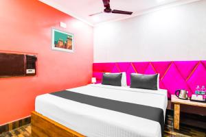 a bedroom with a large bed with a pink wall at Hotel O Barsana in Pātipukur