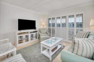 a living room with a tv and a couch and chairs at Beach Club #414 in Saint Simons Island