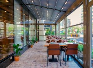 ein Restaurant mit Tischen und Stühlen und großen Fenstern in der Unterkunft Adisson Hotel Baku in Baku