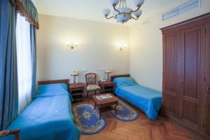 a bedroom with two beds and a table and a chandelier at Guest House na Maloy Nevke in Saint Petersburg