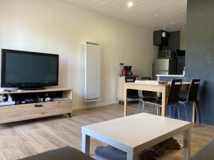 a living room with a flat screen tv and a table at Cocon montagne Rocher du Cerf in Le Lioran
