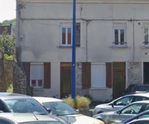 a parking lot with cars parked in front of a building at Aux portes de l'Eure in Bonnières-sur-Seine