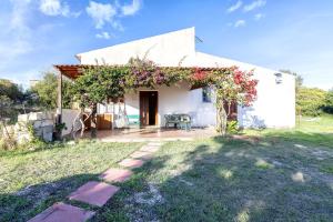 une maison blanche avec une pergola avec des fleurs dessus dans l'établissement Domo Clelia, à Nulvi