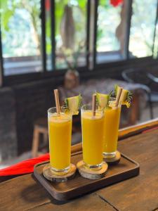 three glasses of orange juice on a wooden tray at Bản Sù - Homestay in Sa Pa