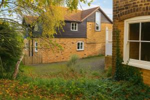 ein Backsteinhaus mit Zaun und Hof in der Unterkunft Watercress Barns in Sittingbourne