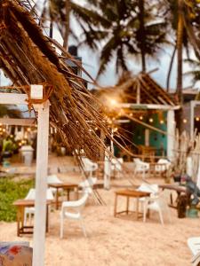 a beach with a straw hut and tables and chairs at Sunset Haven in Habaraduwa Central