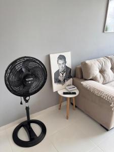 a fan in a living room next to a couch at Apartamento Completo com piscina e play infantil in Ananindeua