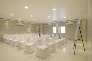 a room with white chairs and a stage in it at Hotel Metropolitan in Jaipur
