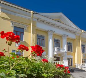 una casa amarilla con flores rojas delante de ella en Guest House na Maloy Nevke, en San Petersburgo