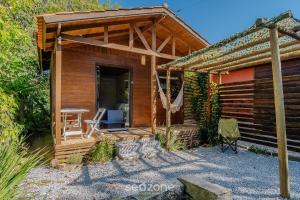 een houten hut met een tafel en een stoel buiten bij Chalés Elegantes e Completos em Imbituba - REL in Praia do Rosa