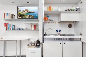 a kitchen with white cabinets and a tv on the wall at CameraPortivè Sea view & AC in Portovenere +5 photos