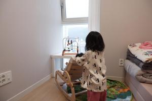 Une petite fille jouant avec un jouet dans une pièce dans l'établissement 광안리해수욕장 30초 베이비 맞춤 풀옵션 패밀리 안심 숙소, à Busan