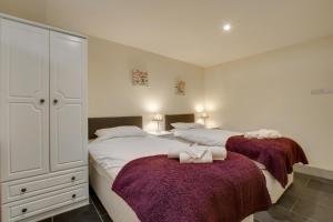 Plym Cottage في Broadhempston: غرفة نوم بسريرين وبطانيات ارجوانية