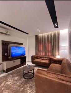 un salon avec deux canapés et une télévision à écran plat dans l'établissement AlShmookh apartments, à Mascate