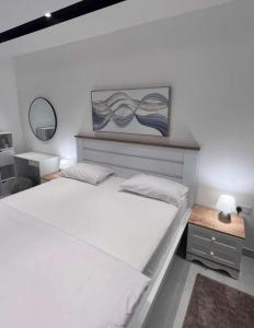 - une chambre blanche avec 2 lits et un miroir dans l'établissement AlShmookh apartments, à Mascate