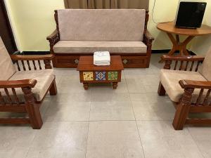 Zimmer mit 2 Stühlen, einem Sofa und einem Tisch in der Unterkunft Vishnu VAASAM Serviced Apartment Srirangam in Tiruchchirāppalli