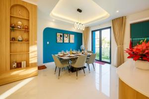 une salle à manger avec des murs bleus et une table et des chaises dans l'établissement The Moon Villa - NOVAWORLD Phan Thiet, à Bình Tú