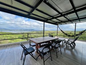ein Tisch und Stühle auf einem Balkon mit einer Hängematte in der Unterkunft El Descanso in Villa Santa Cruz del Lago