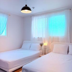 deux lits dans une chambre blanche avec une fenêtre dans l'établissement MAYs GO DUCK Newly built Family Stay KSPO IKEA Lotte World, à Séoul