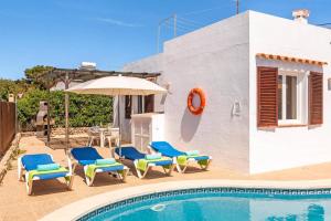 a pool with chairs and an umbrella next to a house at Villa Iris Prima by Villa Plus in Punta Prima