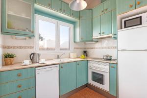 a kitchen with blue cabinets and a white refrigerator at Villa Iris Prima by Villa Plus in Punta Prima