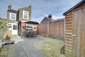 een patio met een hek en een tafel met een parasol bij Millers Cottage in Broadstairs +4 foto's