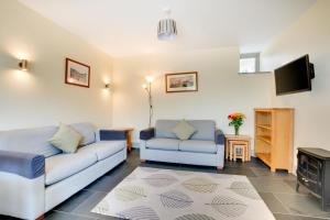 a living room with two couches and a tv at Teign Cottage in Broadhempston
