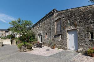 un vecchio edificio in pietra con un tavolo e una porta bianca di Teign Cottage a Broadhempston