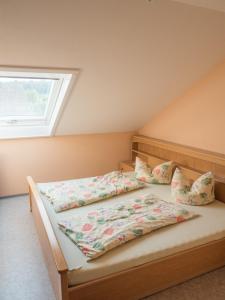 un letto con due cuscini e una finestra di Ferienhof Henn a Tauberrettersheim Altre 24 foto