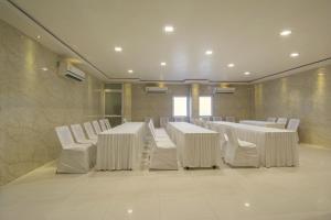 a conference room with white tables and white chairs at Hotel Metropolitan in Jaipur