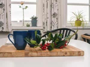 a table with two blue cups and a plant on a cutting board at 4 person holiday home in Rømø in Sønderby