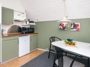 a kitchen with green cabinets and a table with chairs at 4 person holiday home in Rømø in Sønderby