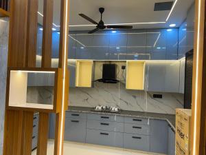 cocina con armarios blancos y ventilador de techo en Singhal Residency, en Greater Noida