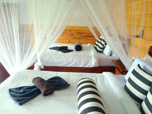 2 bedden in een slaapkamer met witte gordijnen bij NETHSARA cottage in Ella