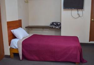 a bedroom with a bed with a purple blanket at Hotel La Quinta de Allison in Lima