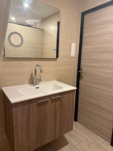 ein Badezimmer mit Waschbecken, Spiegel und Tür in der Unterkunft La chambre clé de la forêt in Métairies-Saint-Quirin