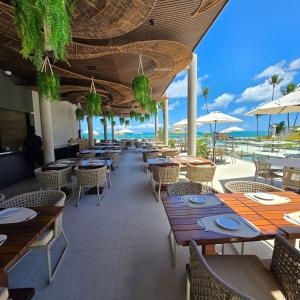 a restaurant with tables and chairs and a view of the ocean at Cais Eco Residência in Porto De Galinhas