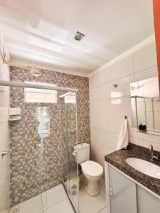 a bathroom with a toilet and a shower and a sink at Pousada Três Praias in Guarapari