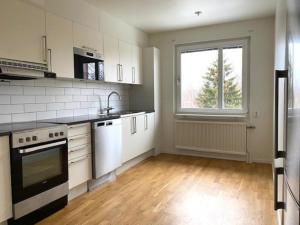 Una cocina con electrodomésticos blancos y una ventana. en Kungsbacken Apartments AB - Blomstervägen 5B, en Katrineholm