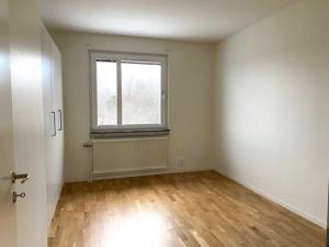 Habitación vacía con ventana y suelo de madera. en Kungsbacken Apartments AB - Blomstervägen 5B, en Katrineholm