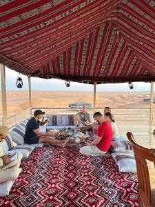a group of people sitting around a table eating food at Desert Vibes Camp in Bidiyah