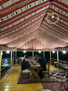 a group of people sitting at a table in a tent at Desert Vibes Camp in Badīyah