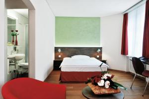 a bedroom with a bed and a red chair at Sorell Hotel Arabelle Bern in Bern +5 photos