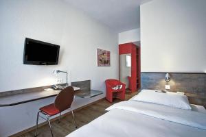 a bedroom with a bed and a desk and a tv at Sorell Hotel Arabelle Bern in Bern