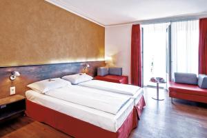 a bedroom with a large bed and a red chair at Sorell Hotel Arabelle Bern in Bern