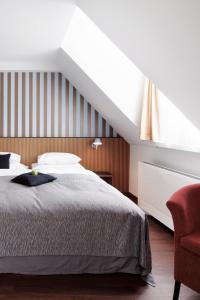 Un dormitorio con una cama y una silla roja. en Sorell Hotel Rütli Niederdorf Zürich, en Zúrich