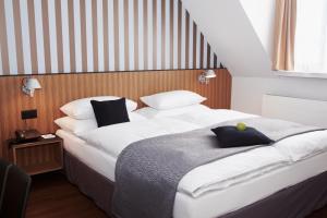 1 dormitorio con 1 cama blanca grande con almohadas negras en Sorell Hotel Rütli Niederdorf Zürich, en Zúrich