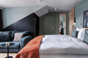 a bedroom with a bed and a blue couch at Sorell Boutique-Hotel St Peter Zürich in Zürich +24 photos