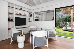 comedor con sillas blancas y TV en NEW Villa 3ch et studio independant Jacuzzi vue mer, en Cul de Sac