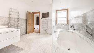 a white bathroom with a tub and a sink at Seaview Penthouse 1 in Alnmouth +1 photo